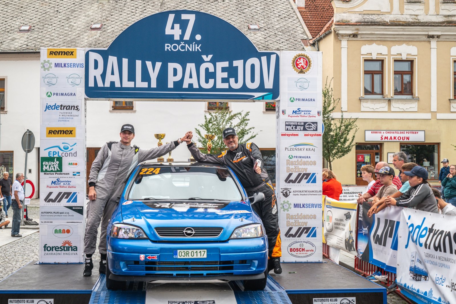 Václav Šejda st. a Jakub Šejda slaví na cílové rampě Rally Pačejov na střeše Opelu Astra OPC